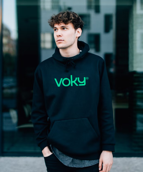 En ung man i stadsmiljö bär en Voky-huvtröja
